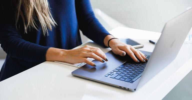 Frau recherchiert am Laptop die Kosten für ihr eigenes Auto