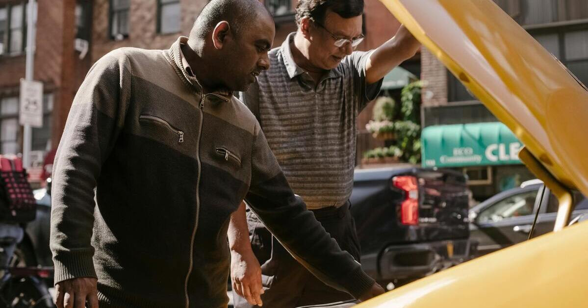 Zwei Personen öffnen die Motorhaube eines Autos im Freien