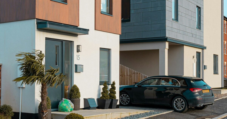 Schwarzes Auto parkt vor modernem Haus mit Hausnummer 15