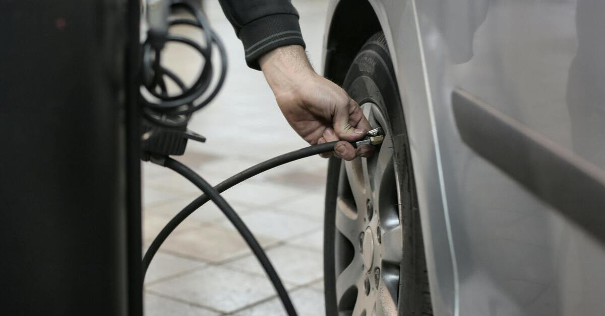 Person prüft Reifendruck an einem Auto