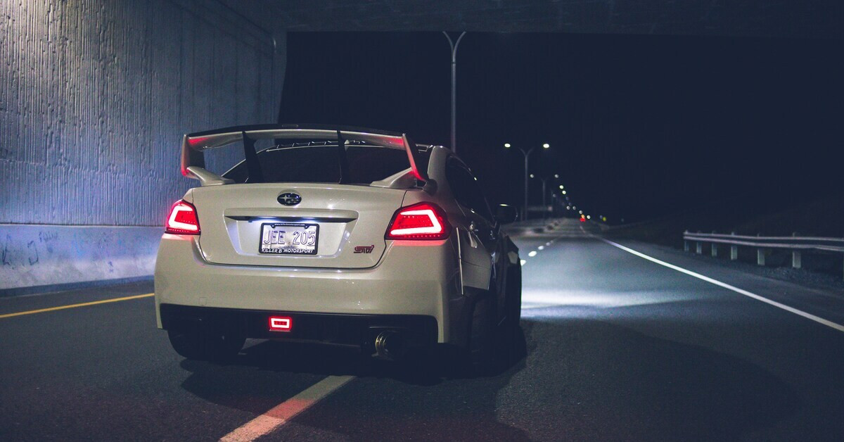 Auto fährt im Dunkeln auf beleuchteter Straße bei Nacht