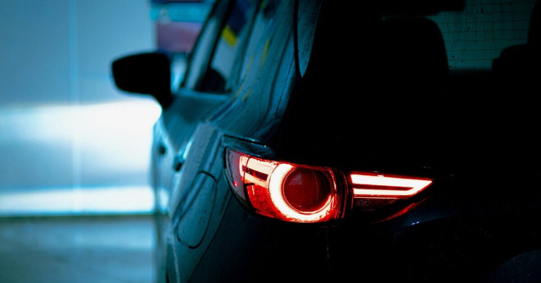 Rotes Rücklicht eines Autos vor einer Wand bei Nacht