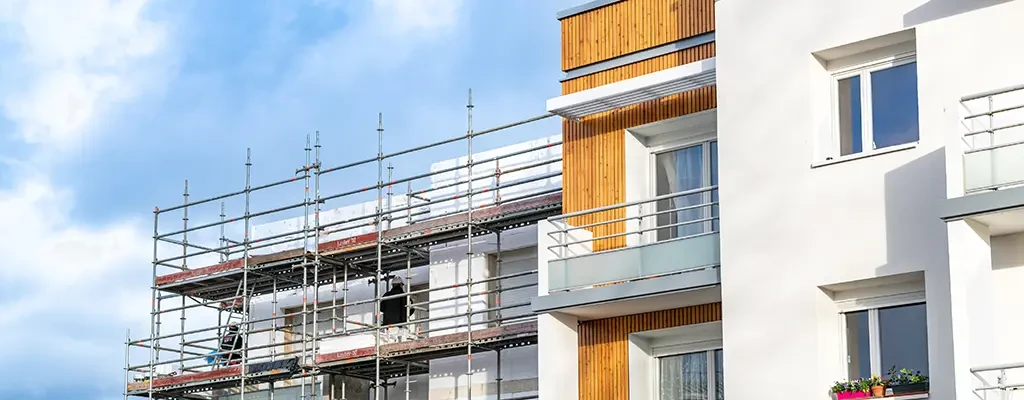 Fassadenbau an einem modernen Wohngebäude mit Gerüst und Holzverkleidung