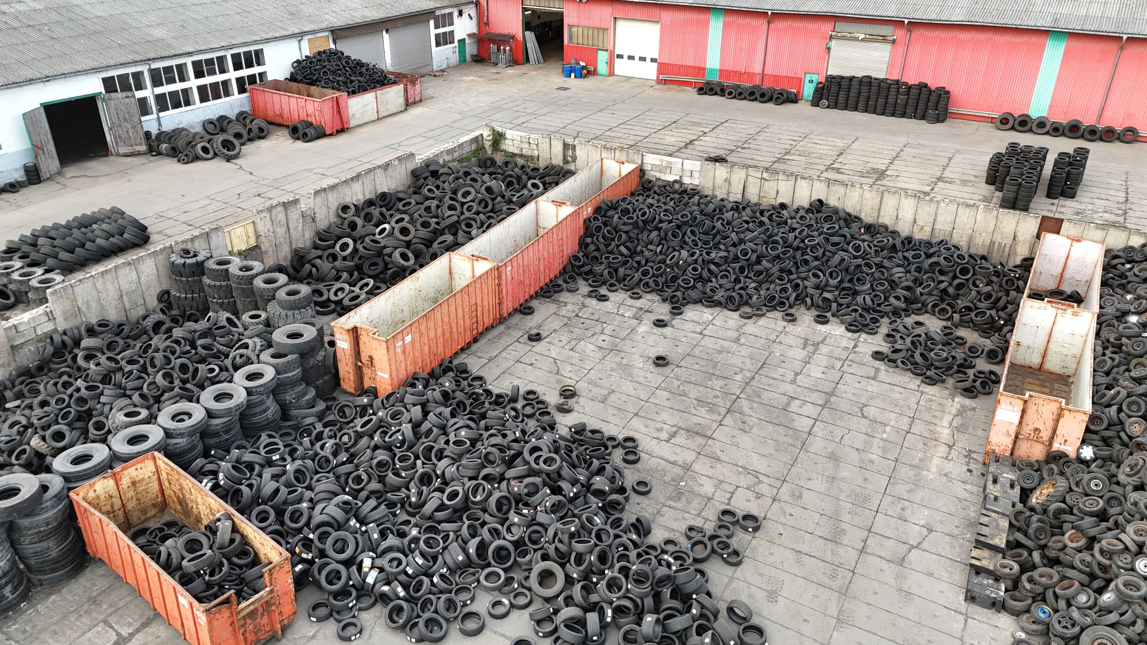 Altreifenlager auf einem Recyclinghof mit zahlreichen gestapelten Reifen und Containern