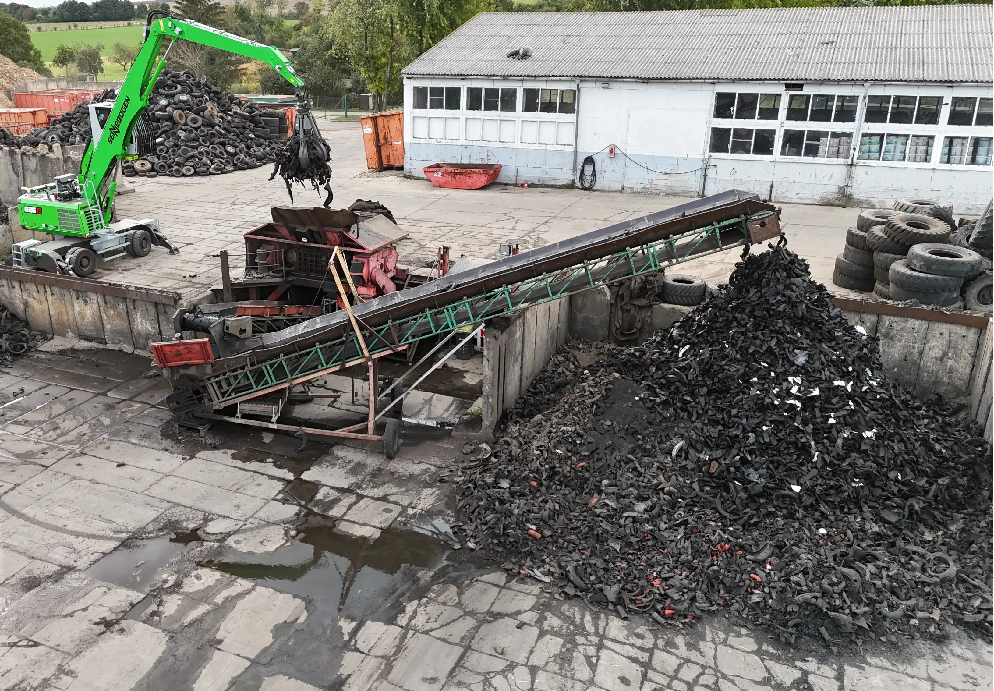 Recyclinganlage mit Förderband und Schrotthaufen auf einem Industriegelände