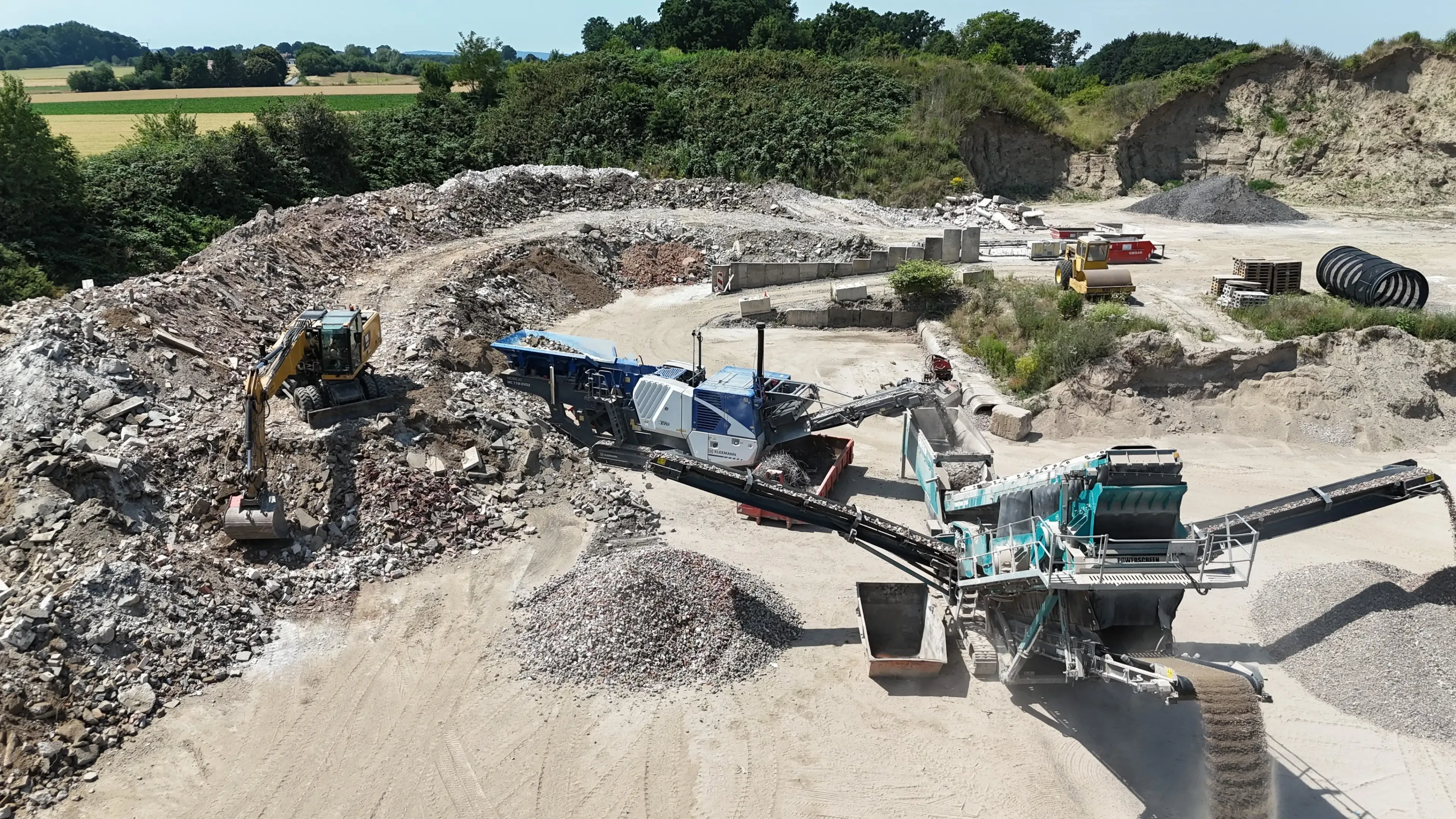Baustelle mit Brechanlage und Bagger bei der Aufbereitung von Bauschutt
