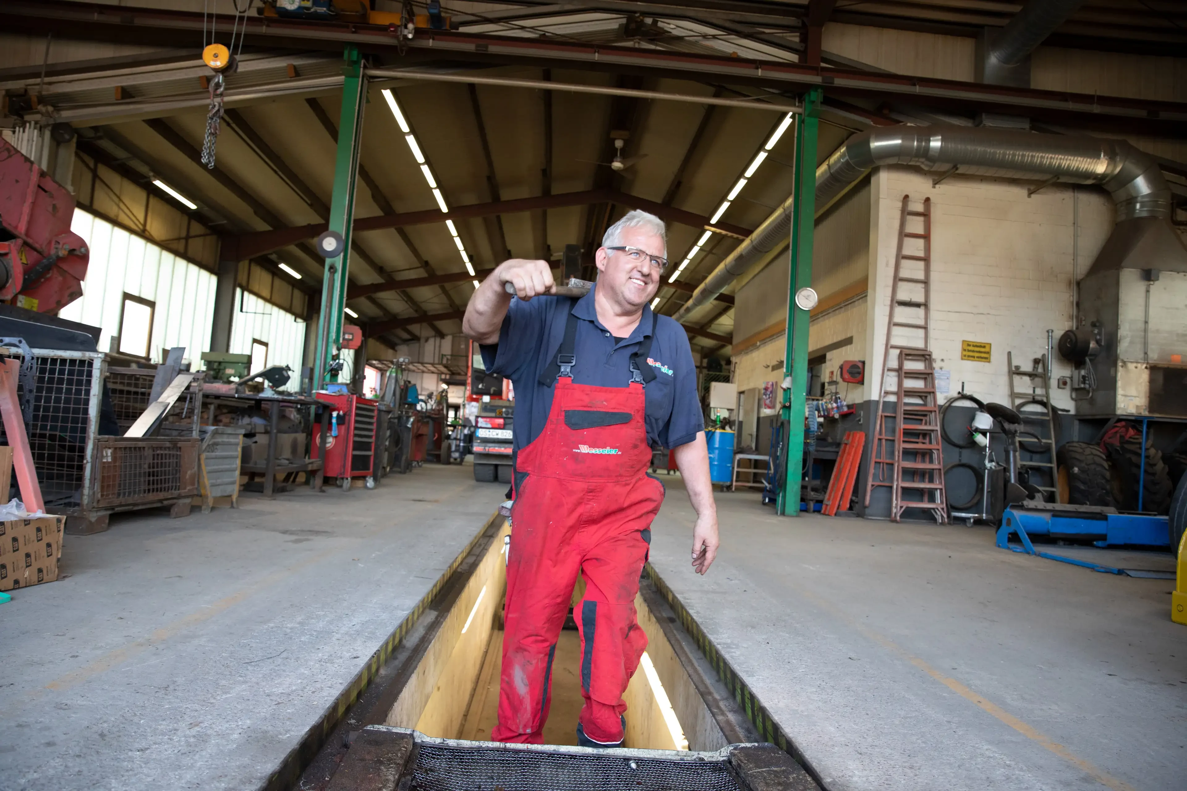Kfz-Mechaniker in roter Latzhose arbeitet in einer Werkstatt