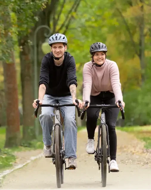 Zwei Personen fahren gemeinsam auf E-Bikes im Park – Symbolbild für E-Bike Leasing