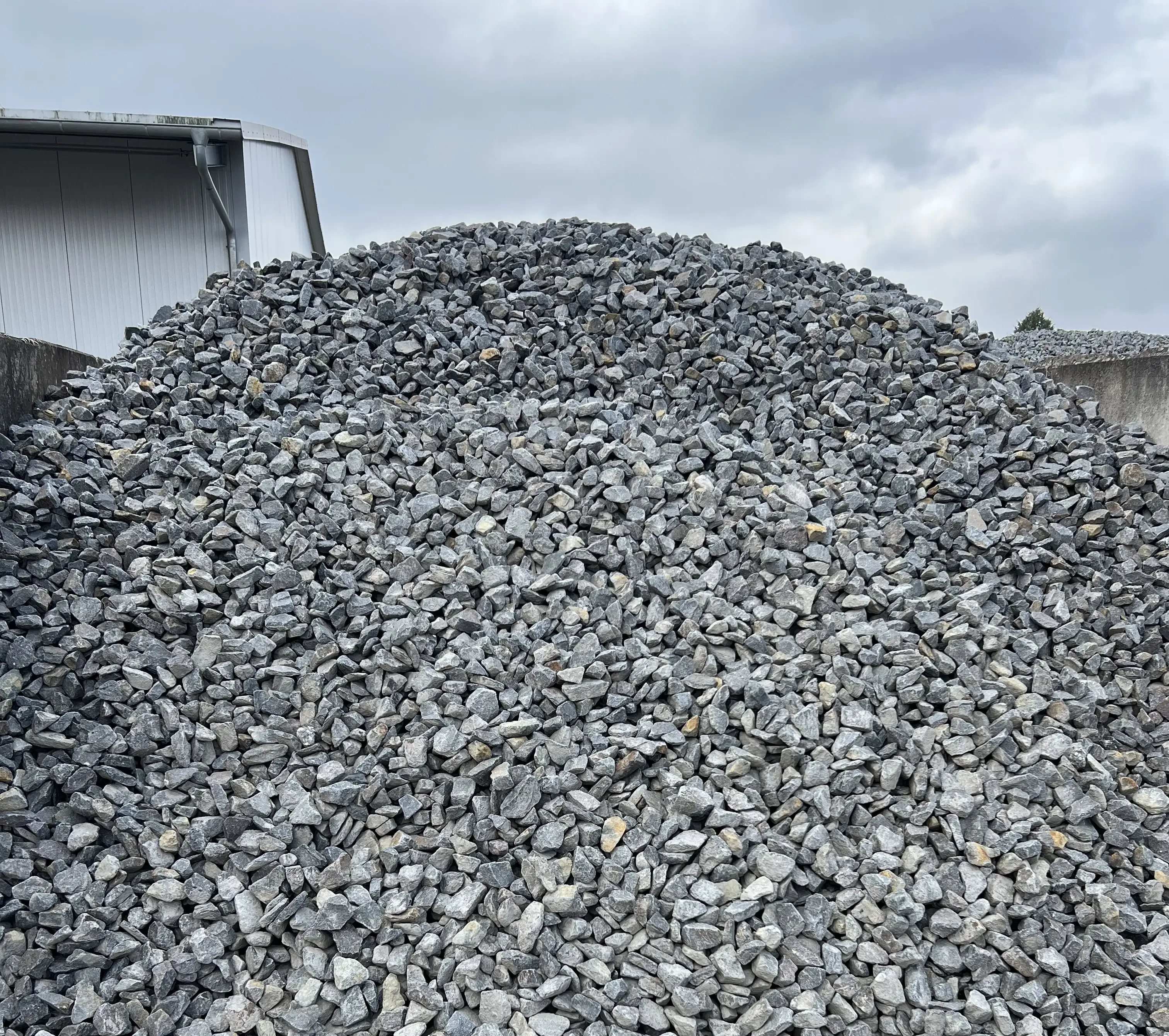 Schotterhaufen auf einem Firmengelände unter bewölktem Himmel