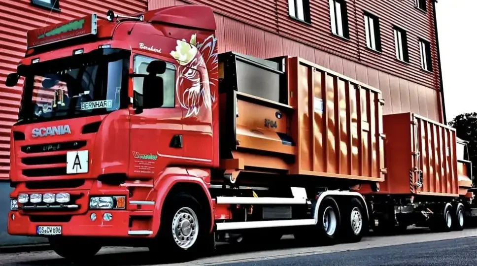 Roter LKW mit Container vor Industriegebäude, Seitenansicht