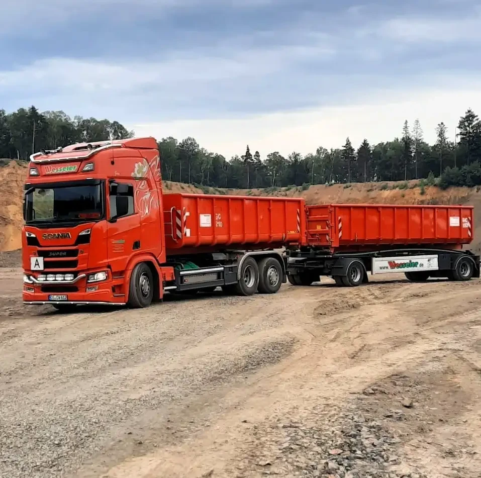 Roter Scania LKW mit Wessler-Aufschrift und Anhänger auf Baustelle