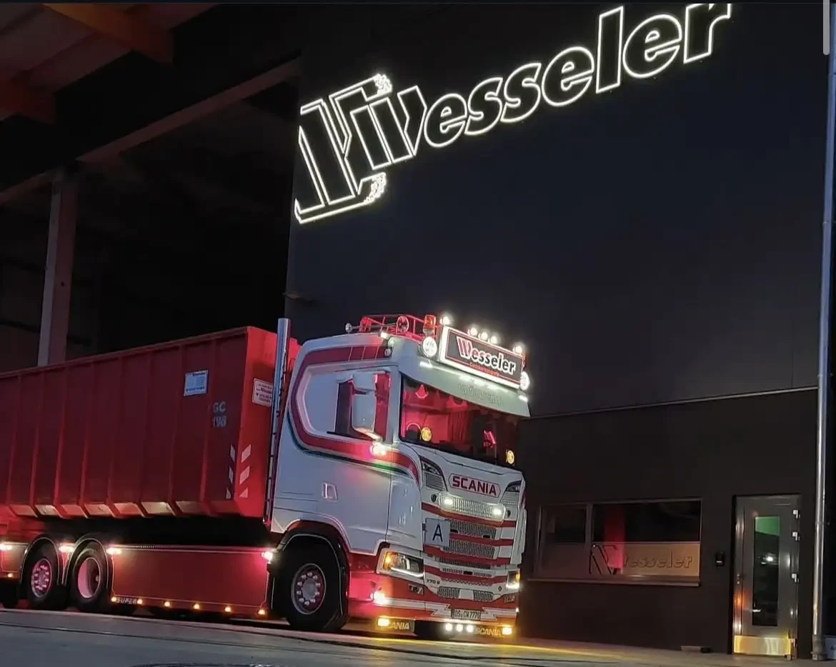 Wesseler LKW bei Nacht vor Firmengebäude mit beleuchtetem Logo
