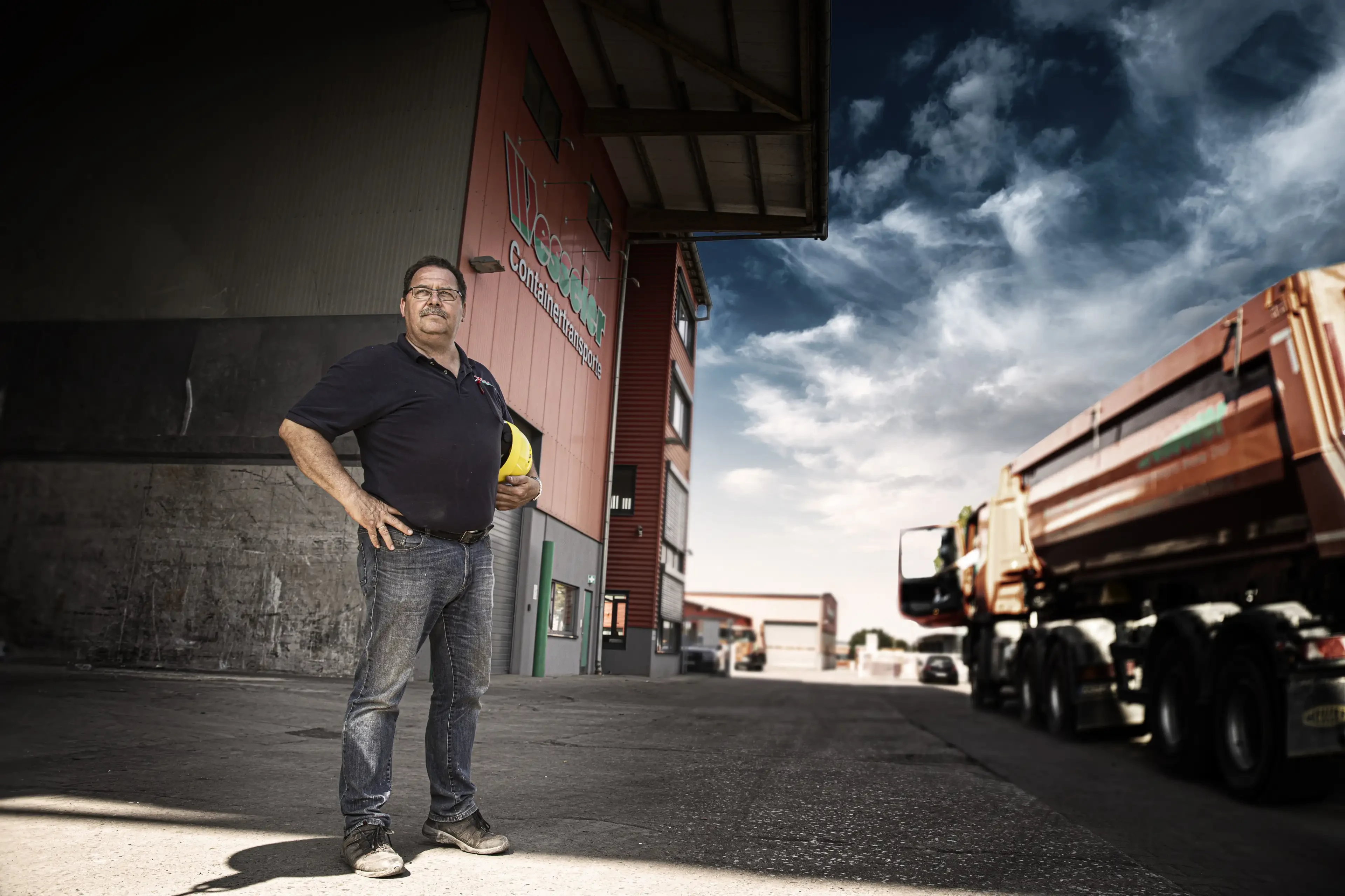 Mitarbeiter vor dem Gebäude von Weconex Containertransporte mit LKW und Bauhelm