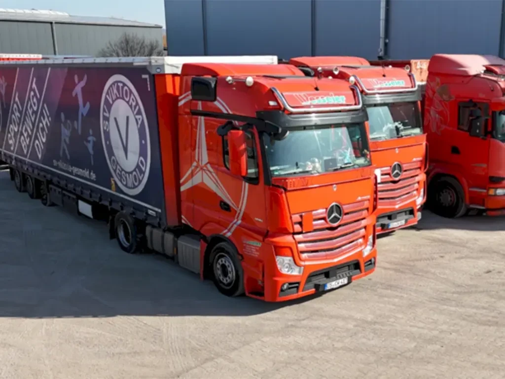 Stellenangebot für Kraftfahrer im Fernverkehr mit roten LKWs auf einem Speditionshof