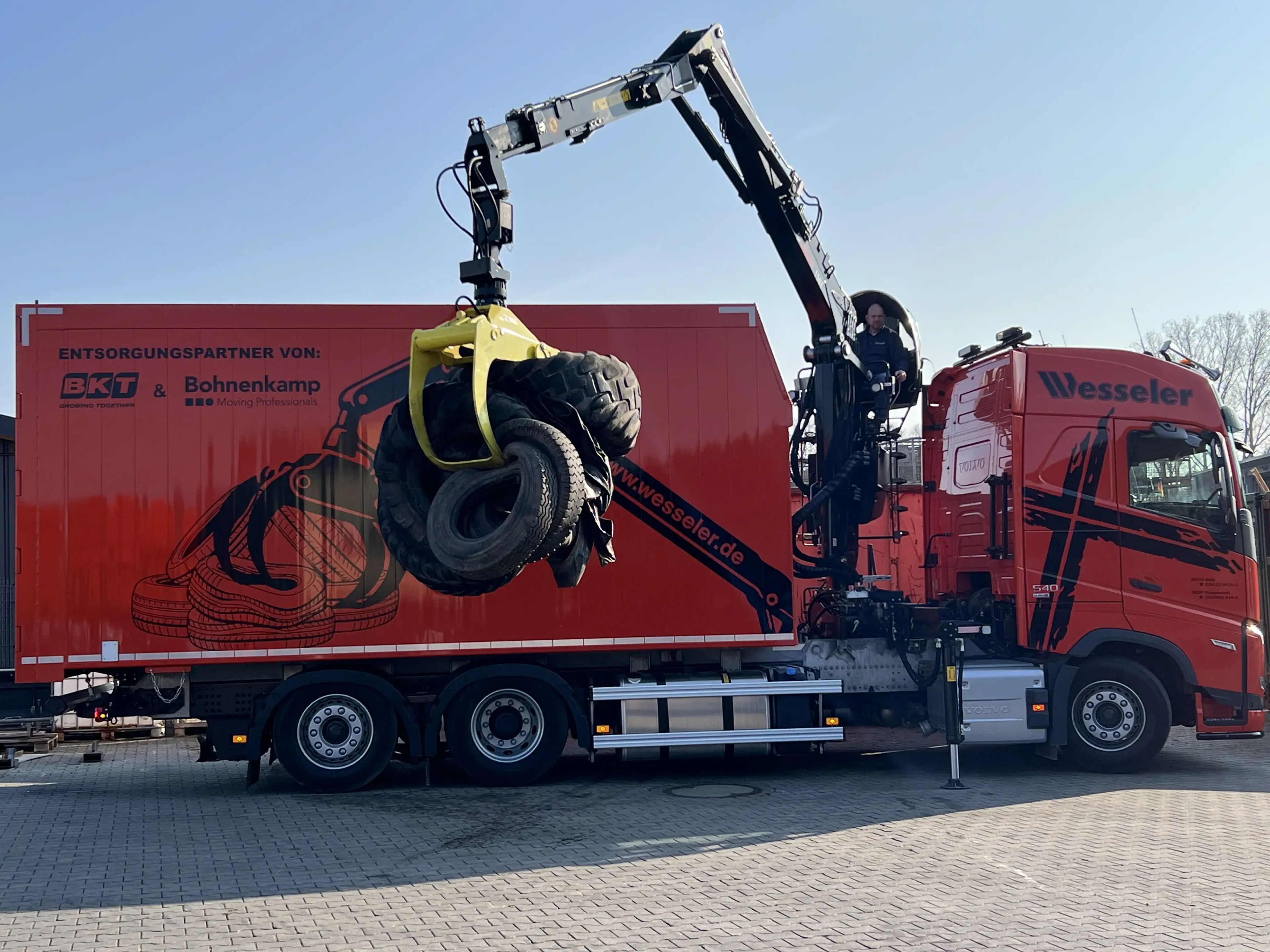 LKW mit Kran von Wesseler beim Verladen von Altreifen vor rotem Bohnenkamp-Container