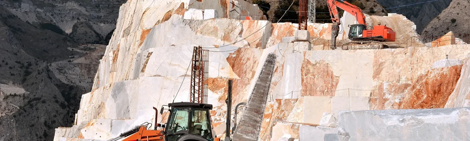 Steinbearbeitung in einem Steinbruch mit Maschinen und Natursteinblöcken