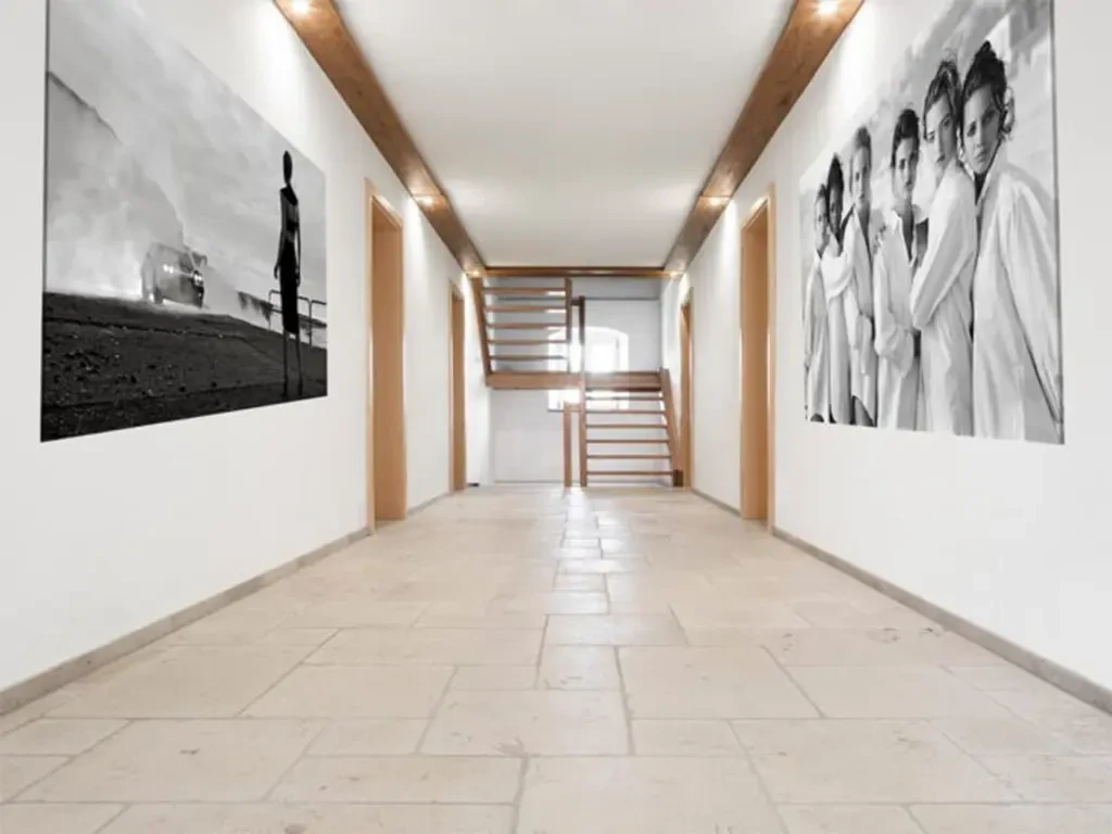 Moderner Flur mit hellen Natursteinfliesen und Wandbildern