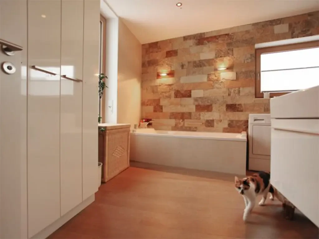 Modernes Badezimmer mit Wandverblender aus Naturstein an der Badewanne