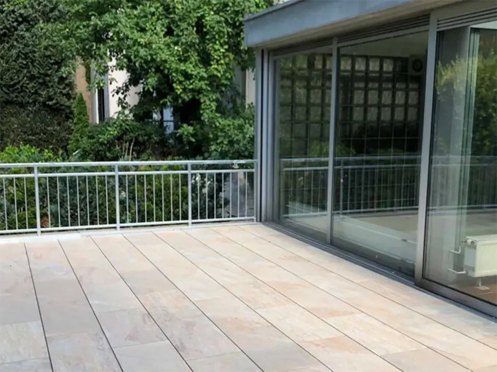 Moderne Terrasse mit hellen Keramikfliesen vor einer Glasfassade
