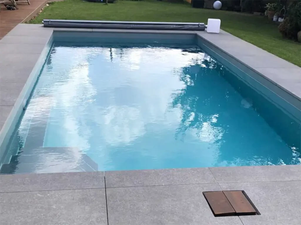 Moderne Poolumrandung aus Steinplatten an einem rechteckigen Swimmingpool