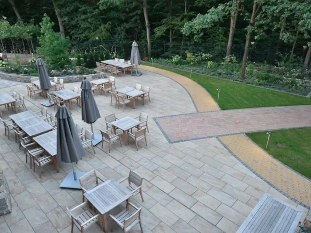 Terrasse mit Mauerabdeckplatten und Sitzgruppen im Grünen
