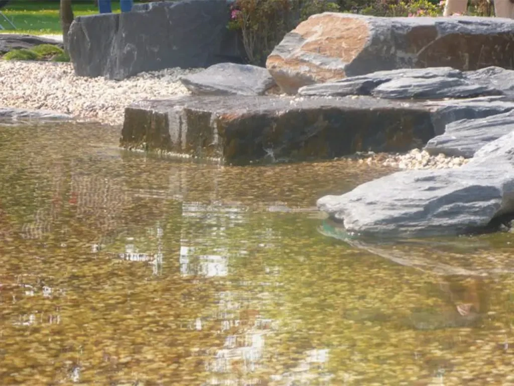 Dekosteine am Teichufer als Gestaltungselement im Garten