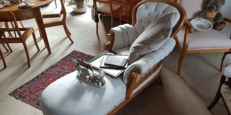 Antike Chaiselongue mit Kissen, Skulptur und Bilderrahmen in klassisch eingerichtetem Wohnzimmer