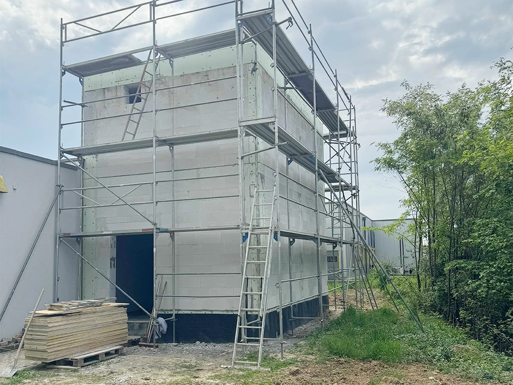 Hochbauarbeiten an einem Rohbau mit Gerüst und Baumaterialien