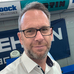 Person vor Banner mit den Marken Lehnert, Martin und Hock Holztechnik