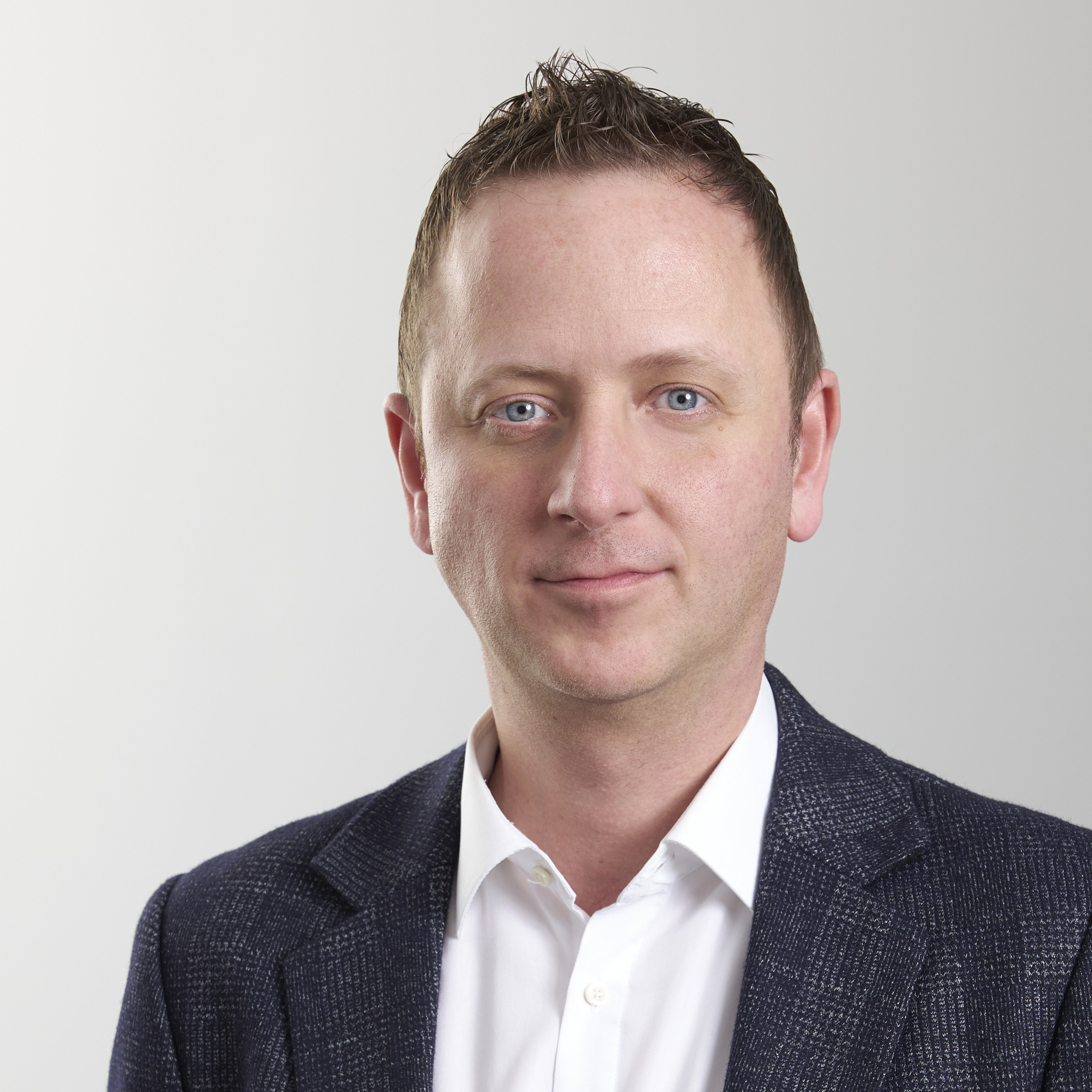 Andreas Reimann im Porträt mit Anzug und weißem Hemd Andreas Reimann im Business-Outfit vor neutralem Hintergrund