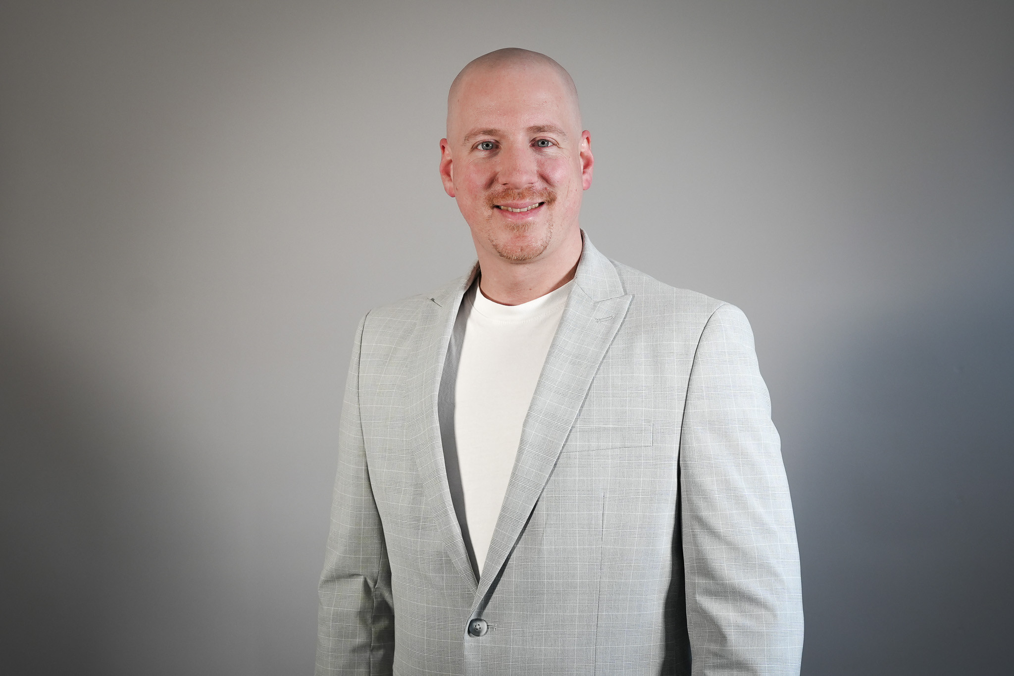 Philipp Stritzel im grauen Sakko vor neutralem Hintergrund