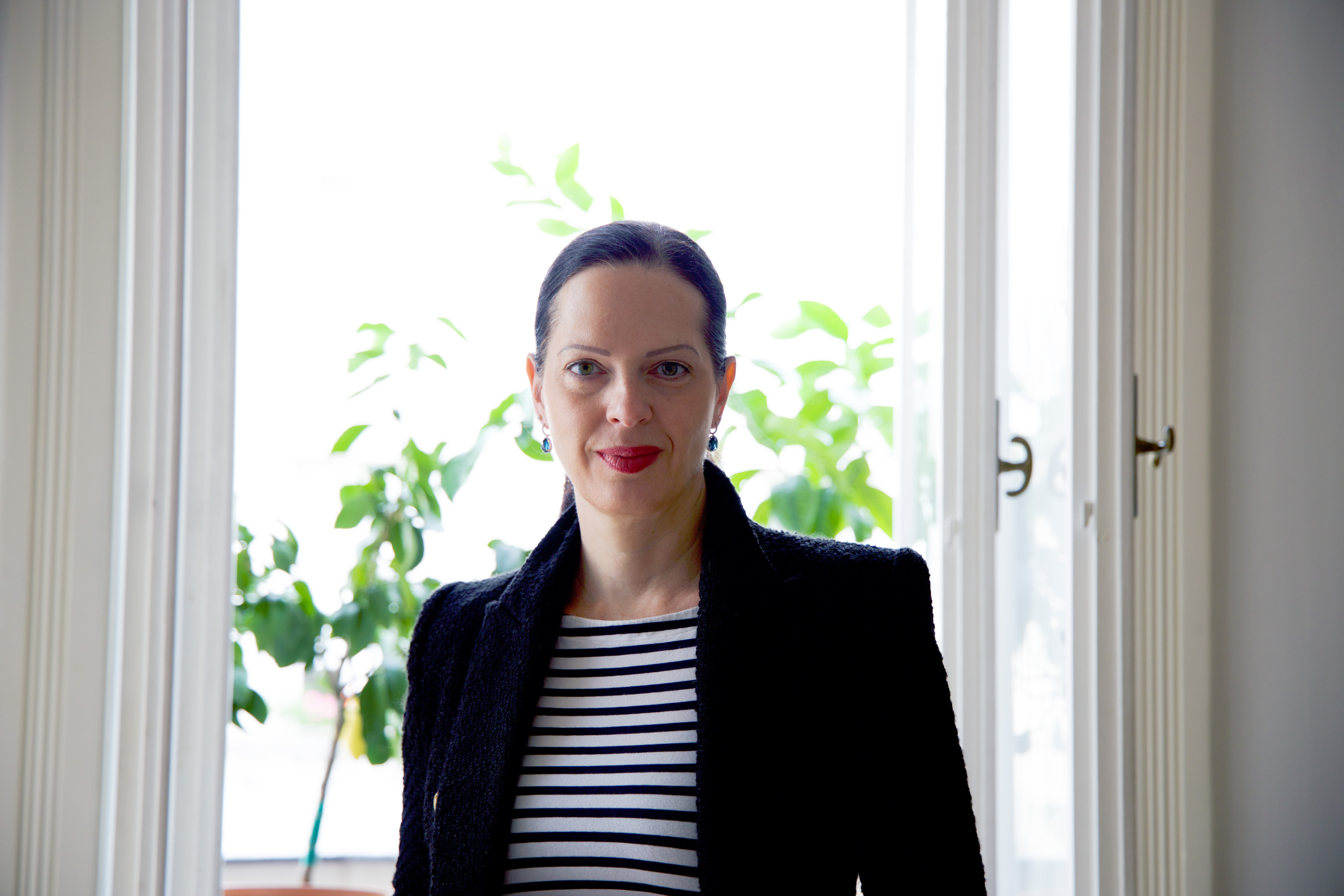 Pauline Pöschl von Enigmasoft steht vor einem Fenster mit Pflanzen im Hintergrund