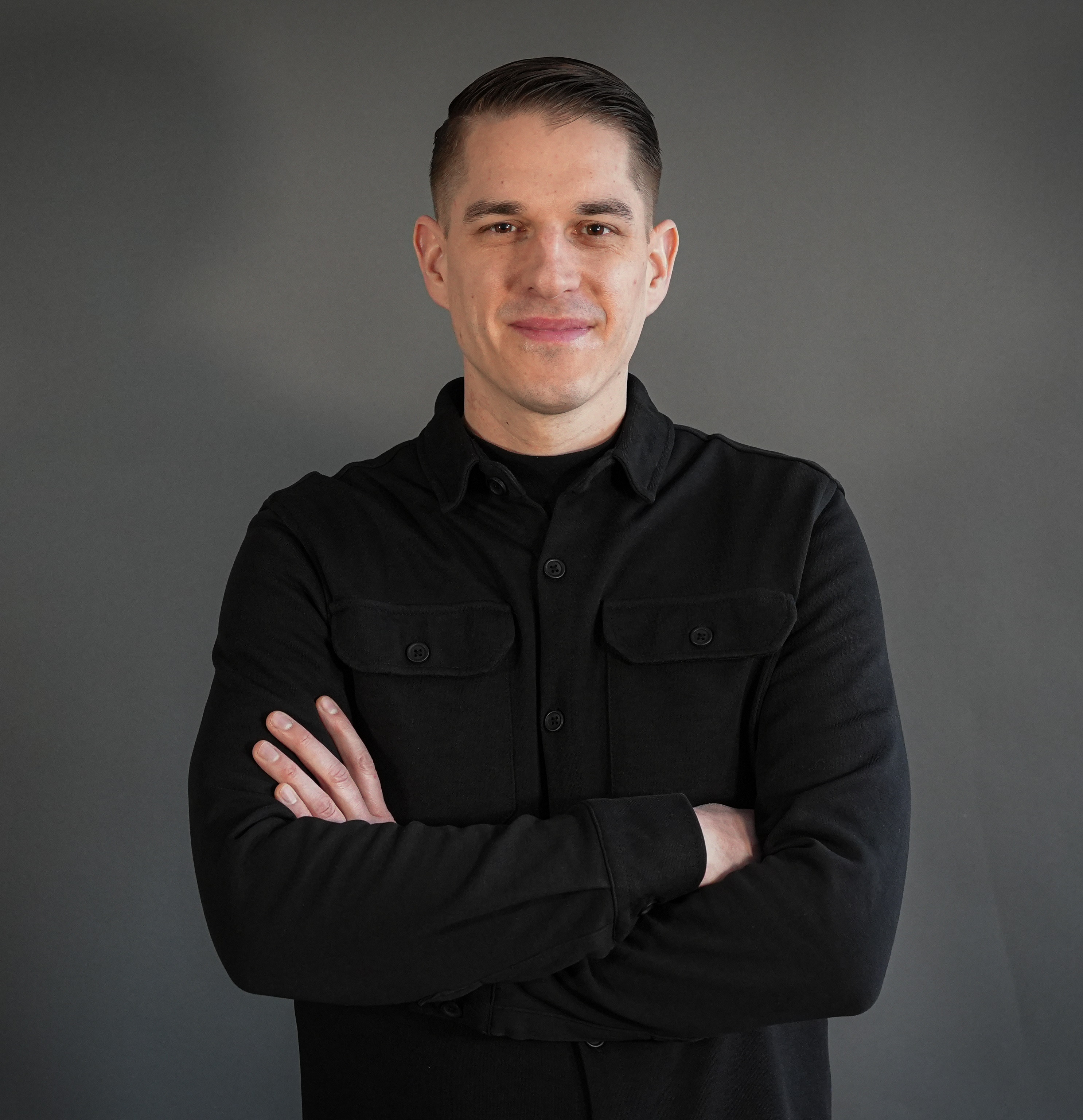 Jan Klaus Dueck im Jahr 2025 mit verschränkten Armen vor grauem Hintergrund