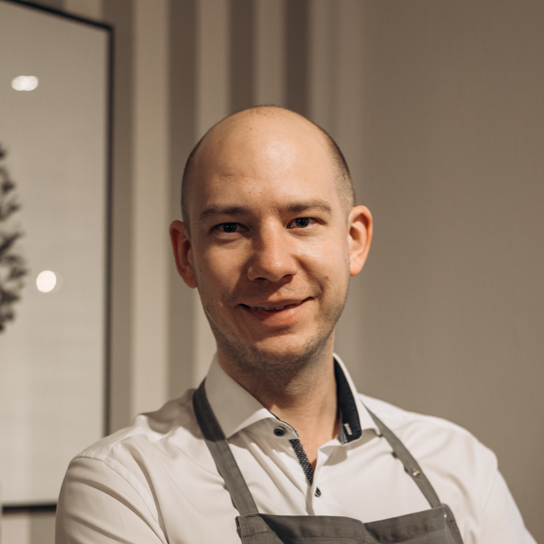 Porträt von Christoph Gabriel mit Schürze in einem modernen Raum