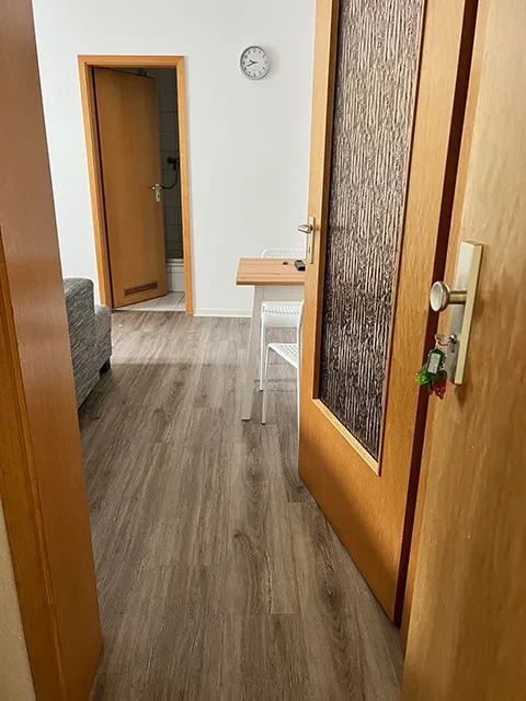 Kleines Apartment – moderner Wohnbereich mit Holztüren und Tisch Blick in ein kleines Apartment mit Holztüren, Tisch und Stuhl