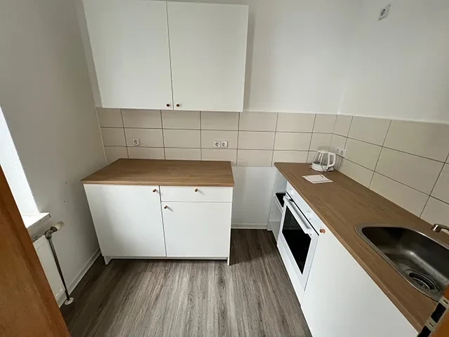 Moderne kleine Küche im Apartment mit weißen Schränken und Holzarbeitsplatte Kleine Apartmentküche mit weißen Schränken und Holzarbeitsplatte
