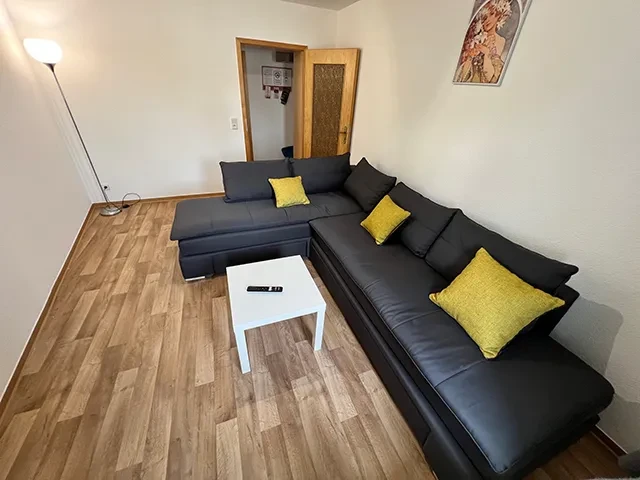 Apartment groß – Wohnzimmer mit Ecksofa und moderner Einrichtung Modernes Apartment mit großem Wohnzimmer, Ecksofa und gelben Kissen