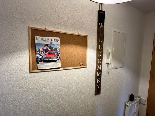 Apartment – Eingangsbereich mit Pinnwand, Mittellandkurier und Willkommensschild Eingangsbereich eines Apartments mit Pinnwand, Zeitung Mittellandkurier und Willkommensschild