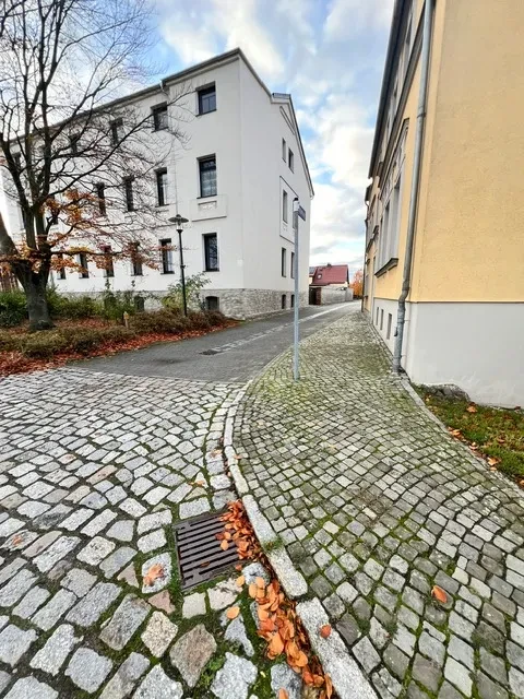 Apartment Groß: Kopfsteinpflasterstraße und Wohnhäuser im Herbst Apartment Groß – Kopfsteinpflasterstraße mit Wohngebäuden im Herbst