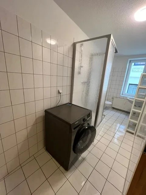 Badezimmer mit Waschmaschine und Dusche in großem Apartment Modernes Badezimmer in einem großen Apartment mit Waschmaschine und Dusche