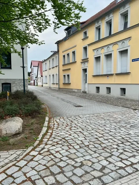 Ruhige Wohnstraße und gelbes Mehrfamilienhaus Ansicht einer ruhigen Wohnstraße mit gelbem Mehrfamilienhaus