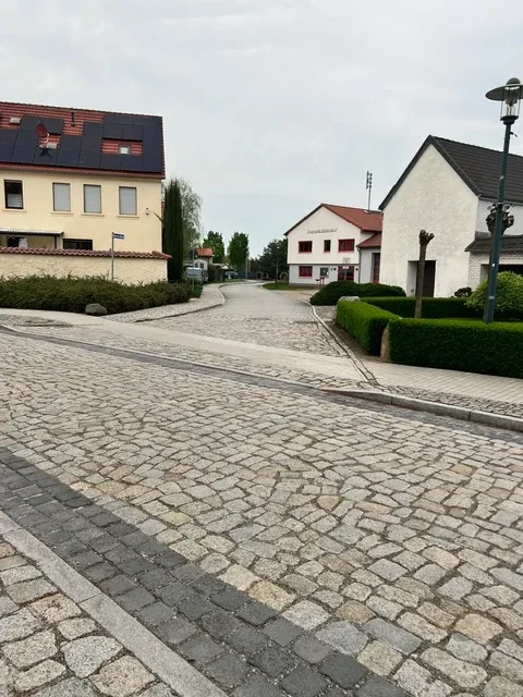 Wohnstraße mit Kopfsteinpflaster und modernen Gebäuden Ansicht einer ruhigen Wohnstraße mit Kopfsteinpflaster und modernen Häusern