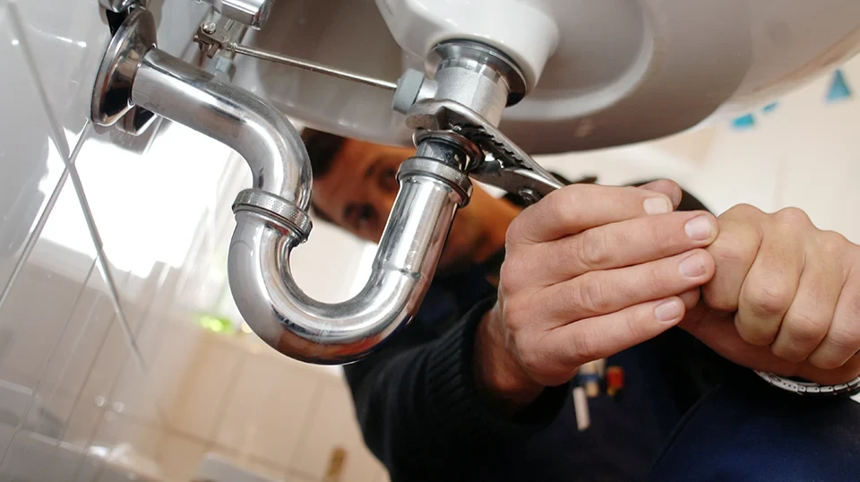 Handwerker vom Abflussdienst repariert Abflussrohr unter Waschbecken mobil vor Ort