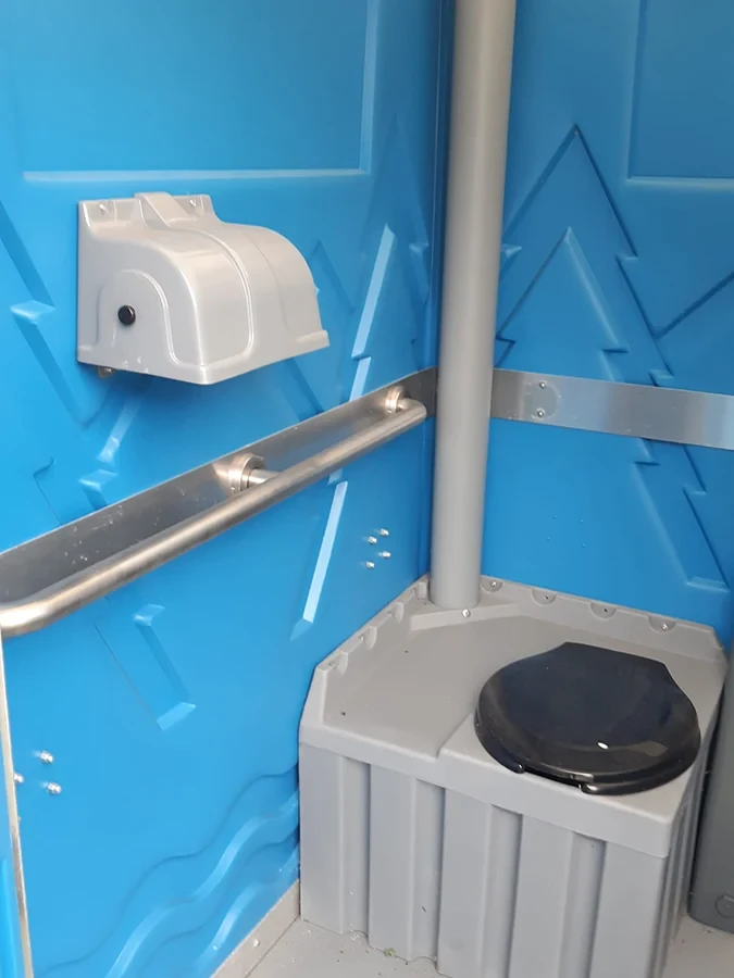 Innenansicht einer mobilen Toilette von Döring Rohrreinigung Toilettenvermietung mit Toilettenpapierhalter und Handlauf.