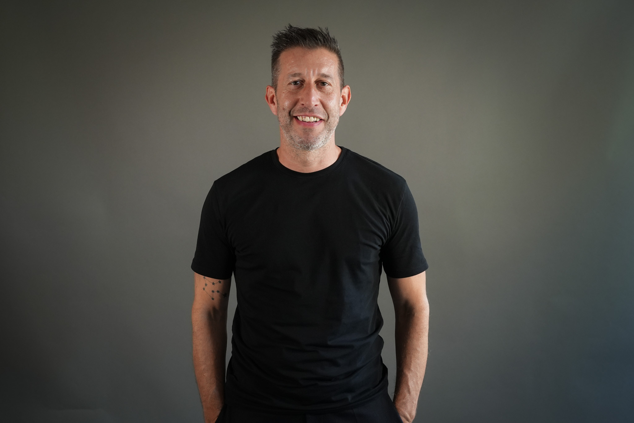Jürgen Dolling in schwarzem T-Shirt vor grauem Hintergrund
