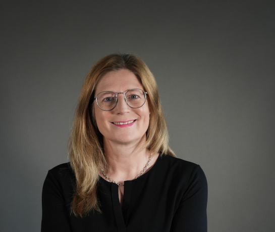 Porträt von Sonja – Frau mit blondem Haar und schwarzer Kleidung Porträtfoto einer Frau namens Sonja mit schulterlangem blondem Haar und schwarzer Kleidung vor grauem Hintergrund