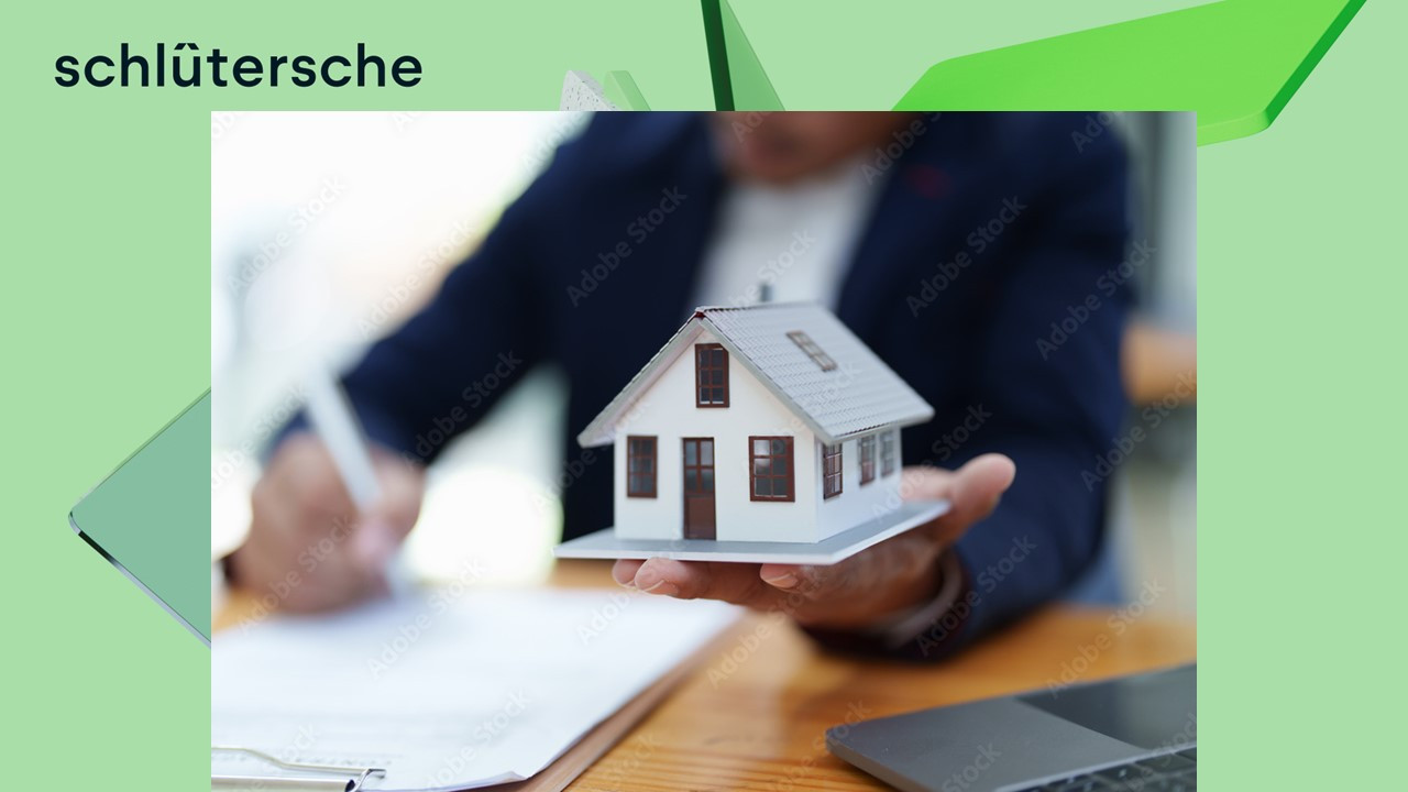 Immobilienmakler hält ein Modellhaus und unterschreibt einen Vertrag