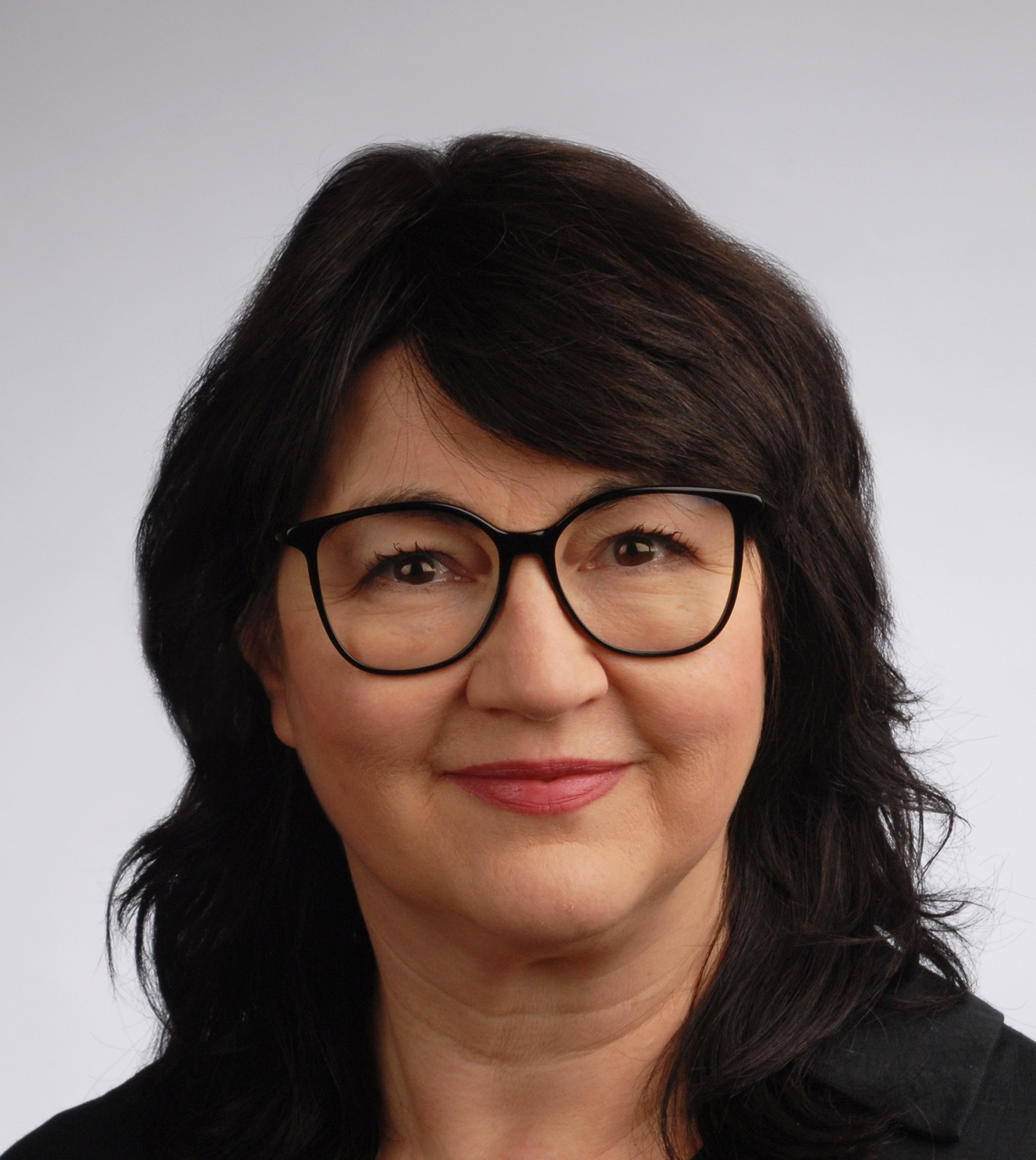 Porträtfoto von Inga mit dunklen Haaren vor neutralem Hintergrund