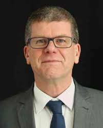 Porträtfoto von Dr. Krause im Anzug vor schwarzem Hintergrund