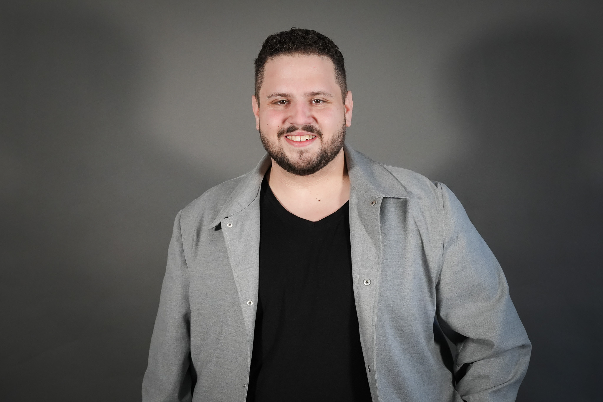 Patrick Heinrich in grauer Jacke vor neutralem Hintergrund